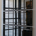 Decorative wall mirror with antiqued metal frame on a white wall