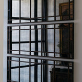 Decorative wall mirror with antiqued metal frame on a white wall