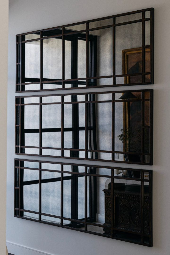 Decorative wall mirror with antiqued metal frame on a white wall