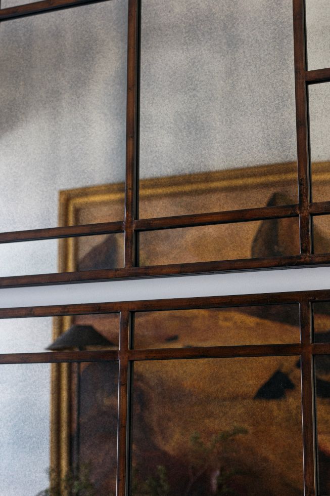 Decorative large rectangular antuiqued mirror with a rustic bronze metal frame, displayed on a wall.
