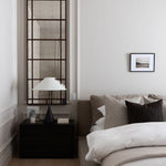 Modern bedroom with an antiqued mirror, bed, nightstand, and lamp.