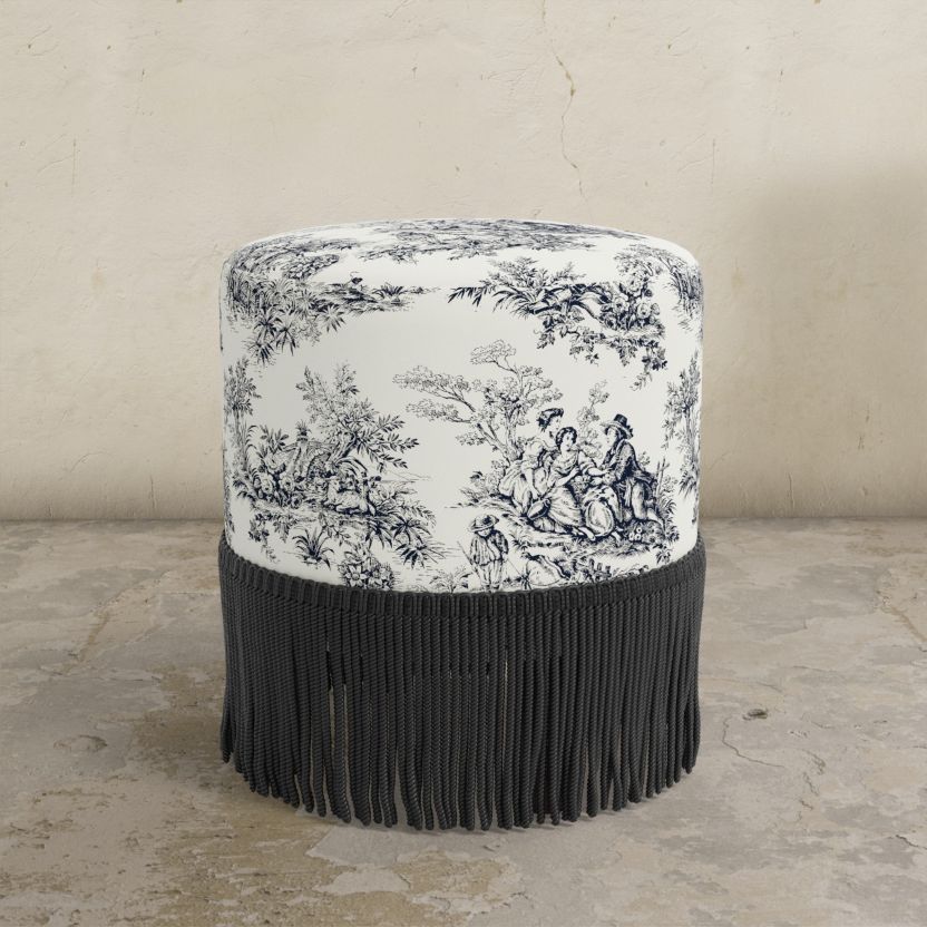 Round ottoman with black and white patterned top and black fringe on a beige background