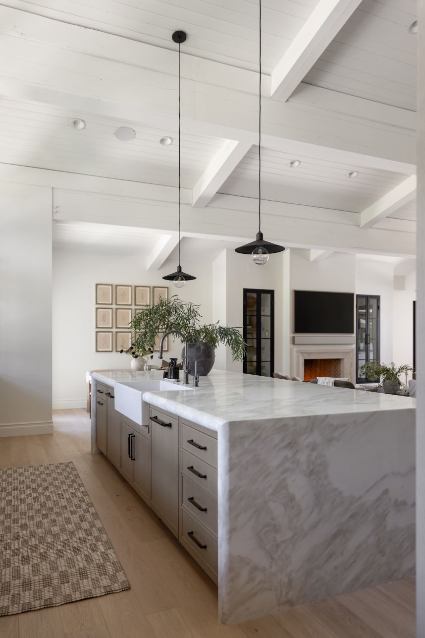 Modern kitchen with McCoy pendants over a marble island and white walls