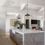 Modern kitchen with McCoy pendants over a marble island and white walls