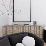 The Oslo dresser with books, photos and a vase and artwork above behind a gray sofa with pillows.