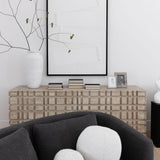 The Oslo dresser with books, photos and a vase and artwork above behind a gray sofa with pillows.