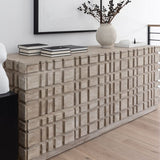 A gray washed Oslo dresser made of reclaimed Douglas Fir wood, featuring a geometric pattern on the front. It is placed in a room with a vase on top and books stacked on the left side.