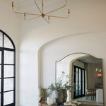 Elegant interior with a gold chandelier, large mirror, and wooden bench.