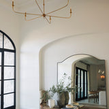 Elegant interior with a gold chandelier, large mirror, and wooden bench.