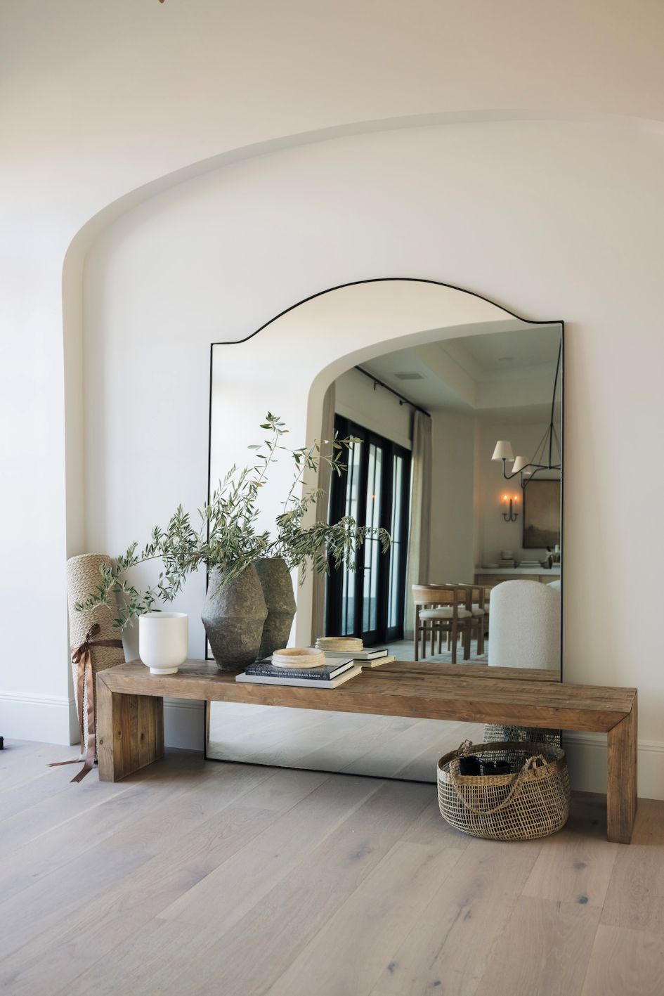 Large mirror on a rustic wooden bench made or reclaimed pine with decorative items in a front hallway