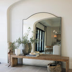 Large mirror on a rustic wooden bench made or reclaimed pine with decorative items in a front hallway