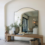 Large mirror on a rustic wooden bench made or reclaimed pine with decorative items in a front hallway