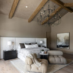 Modern bedroom with wooden beams, a Tirrell Large Black candle style chandelier, and neutral decor.