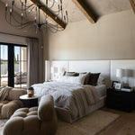 Modern bedroom with a Tirrell Large Black candle-style chandelier, bed, and sitting area.