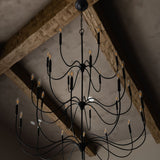 Tirrell Large Black candle style chandelier hanging from a ceiling with wooden beams