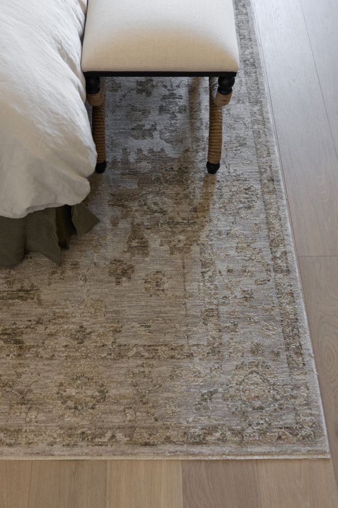 Willa patterned power loomed area rug on a wooden floor with a bed and bench in the background