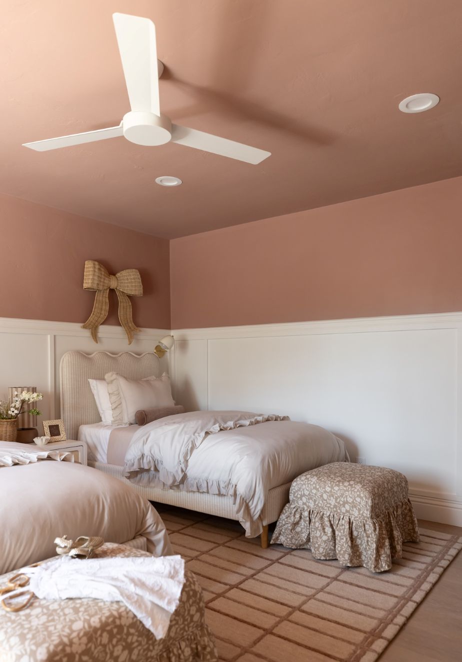 Bedroom with a bed and the Eloise ottoman on a patterned rug.