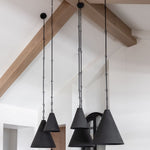 Three black pendant lights in two sizes hanging from the ceiling with wooden beams in the background.