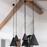 Three black pendant lights in two sizes hanging from the ceiling with wooden beams in the background.