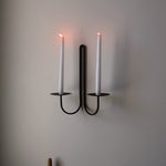 Elm double scnce with two lit candles on a plain wall.