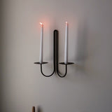 Elm double scnce with two lit candles on a plain wall.