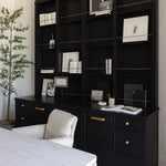 White wooden unique desk and black bookshelf with decorative items in a home workspace with a chair and plant.