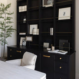 White wooden unique desk and black bookshelf with decorative items in a home workspace with a chair and plant.