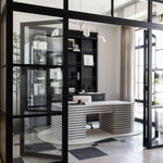 Modern home office workspace with glass walls and a unique wooden white desk.