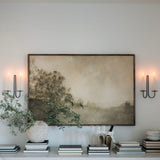 Modern interior with a large abstract landscape wall art, decorative items on a shelf, and wall sconces.