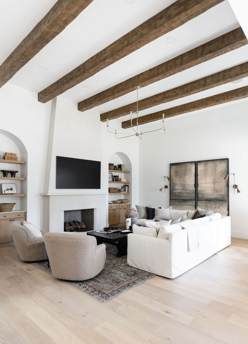 Modern living room with white walls, wooden beams, nottaway large modern chandelier for high ceilings, sofas, chairs, fireplae, tv and other decorative elements