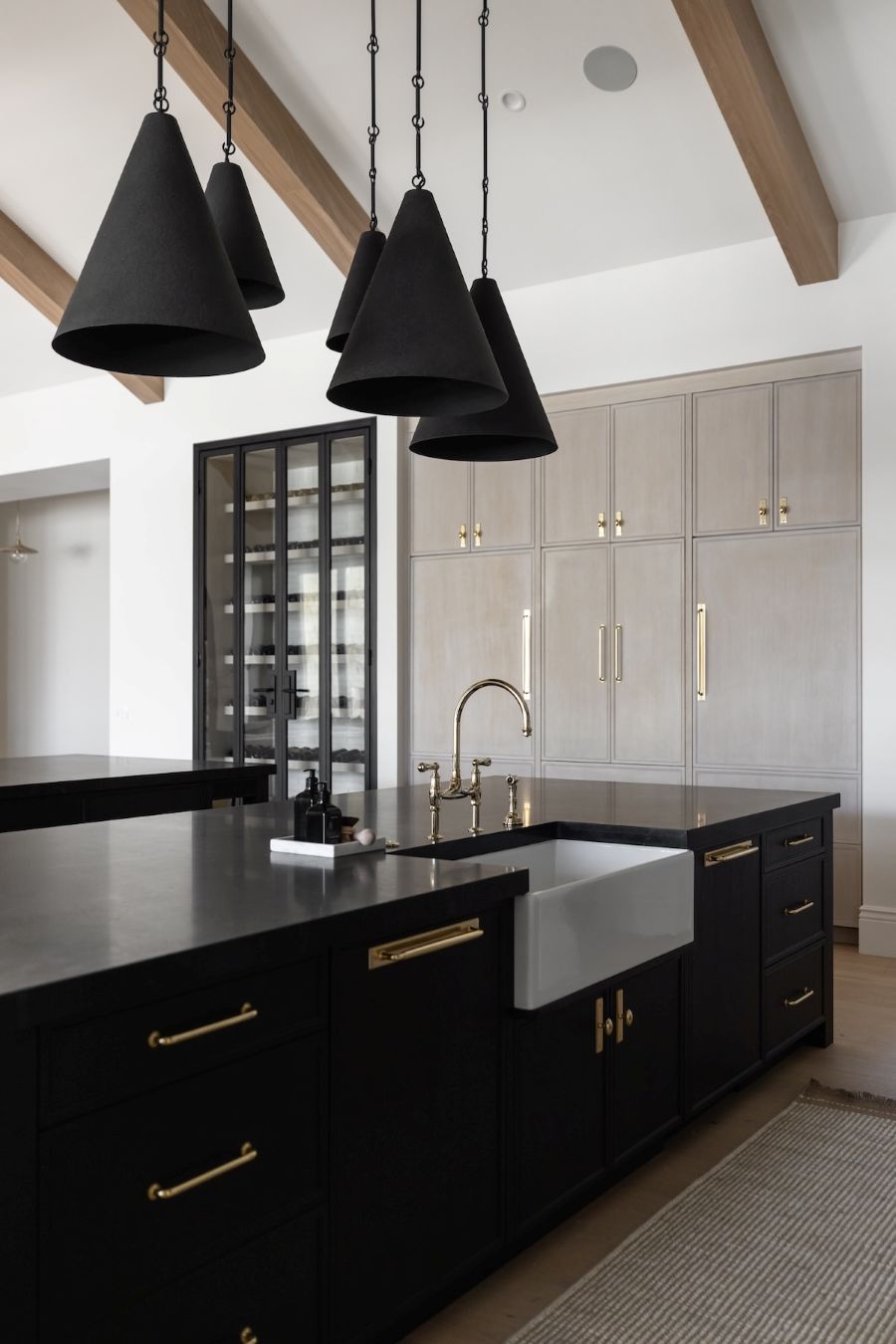 Modern kitchen with black island, pendant lights, and cabinets.