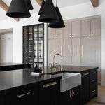 Modern kitchen with black island, pendant lights, and cabinets.