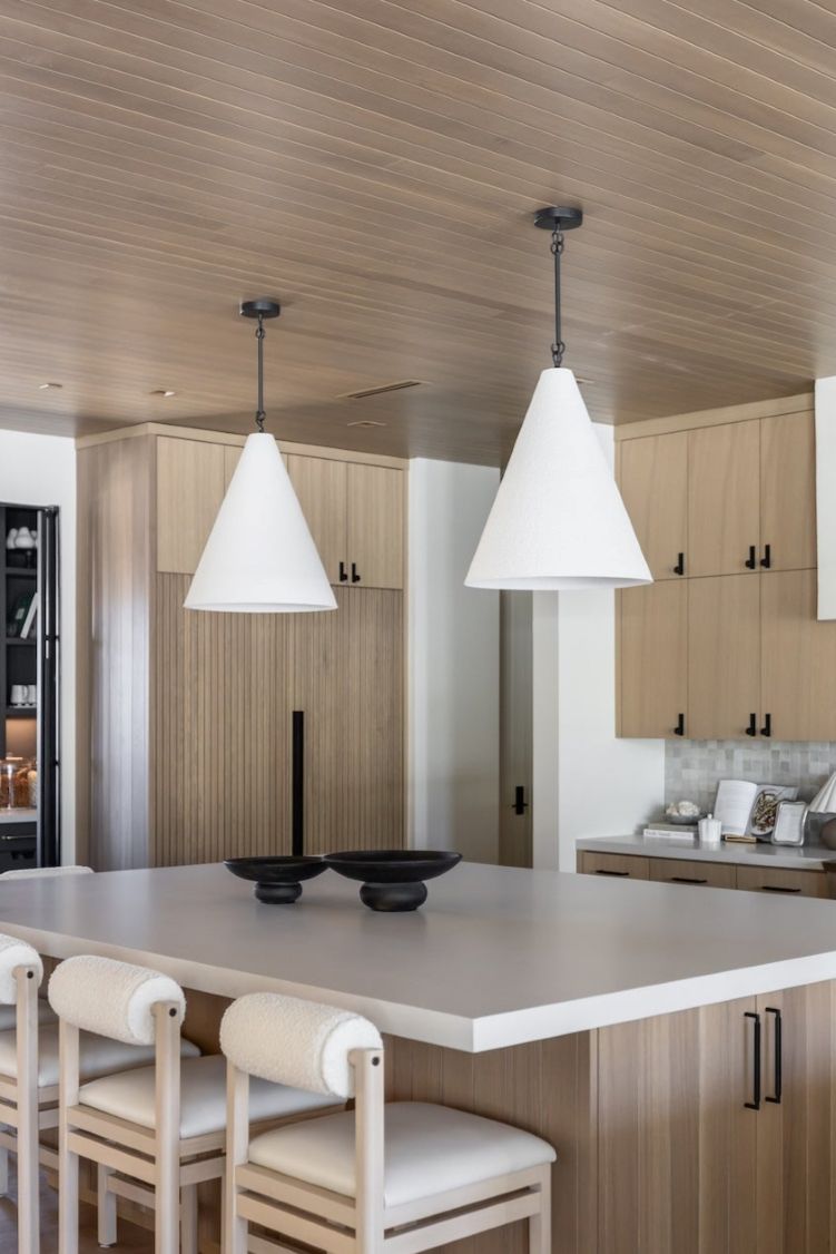 Modern kitchen with wooden cabinets, white countertops, and Grazia pendant lights over kitchen island.