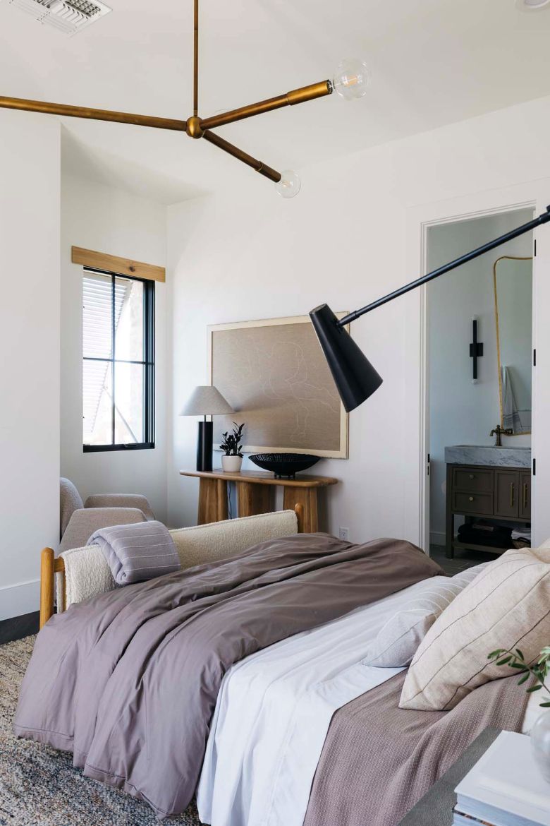 Modern bedroom with a Regina Andrew Talon chandelier, bed, lamp, and window.