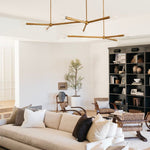 Modern living room with beige sofa, gold modern chandelier, and bookshelf.
