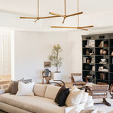 Modern living room with beige sofa, gold modern chandelier, and bookshelf.