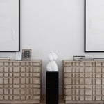 Two Oslo statement dressers beside each other with books on top and a statue in between and art on the walls behind them