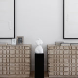 Two Oslo statement dressers beside each other with books on top and a statue in between and art on the walls behind them